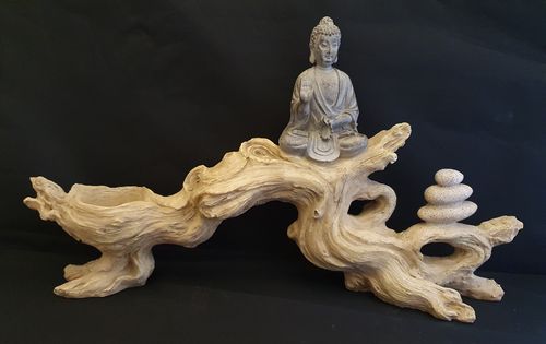 grauer Buddha auf einem hellen Baumstamm